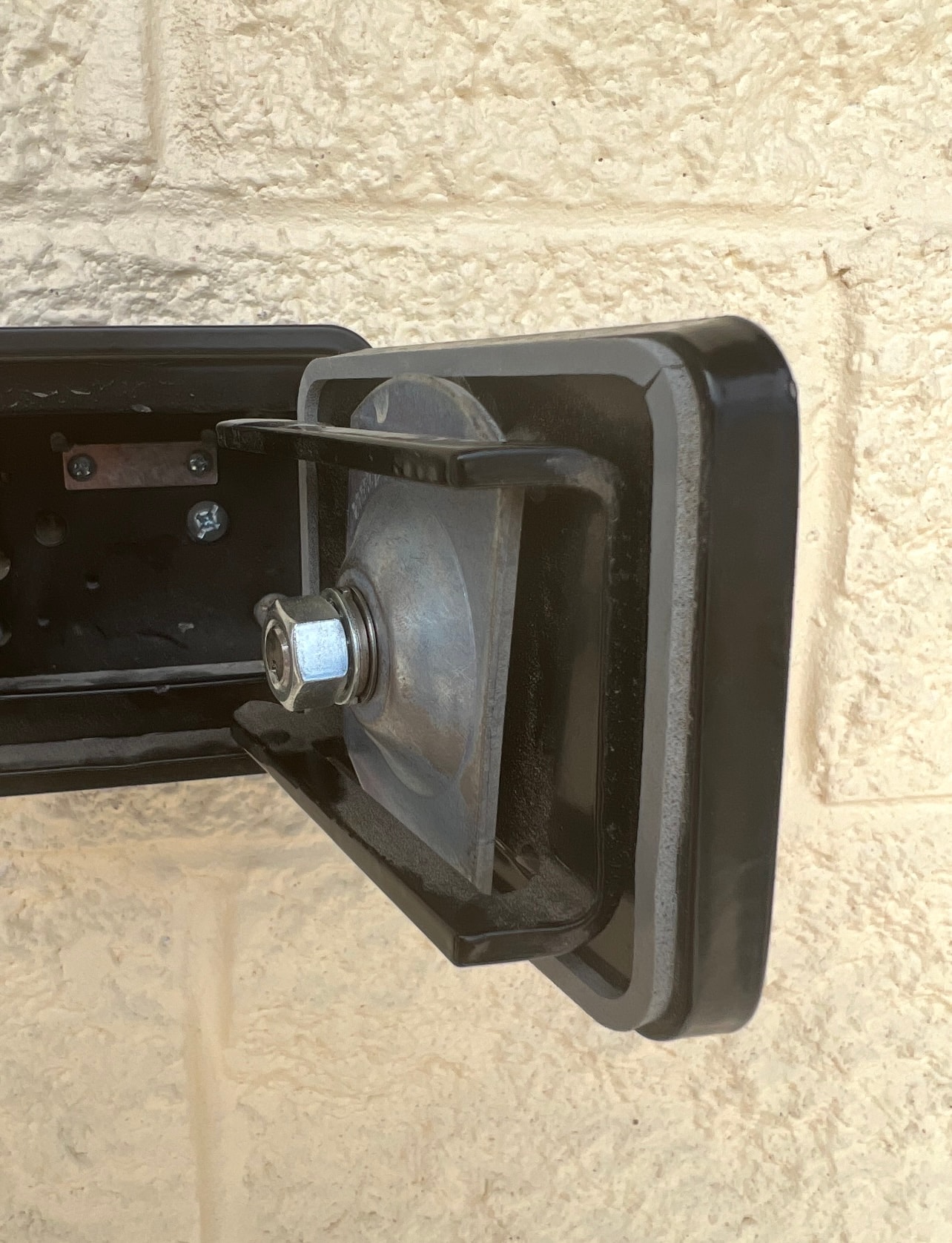 Black metal hinge mounted on stone wall