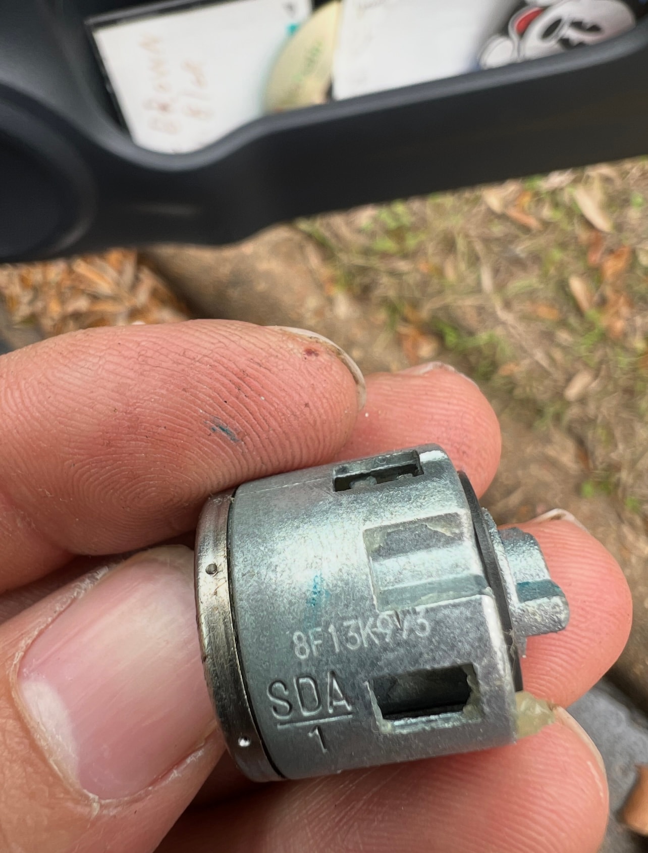 Hand holding metal automotive part outdoors