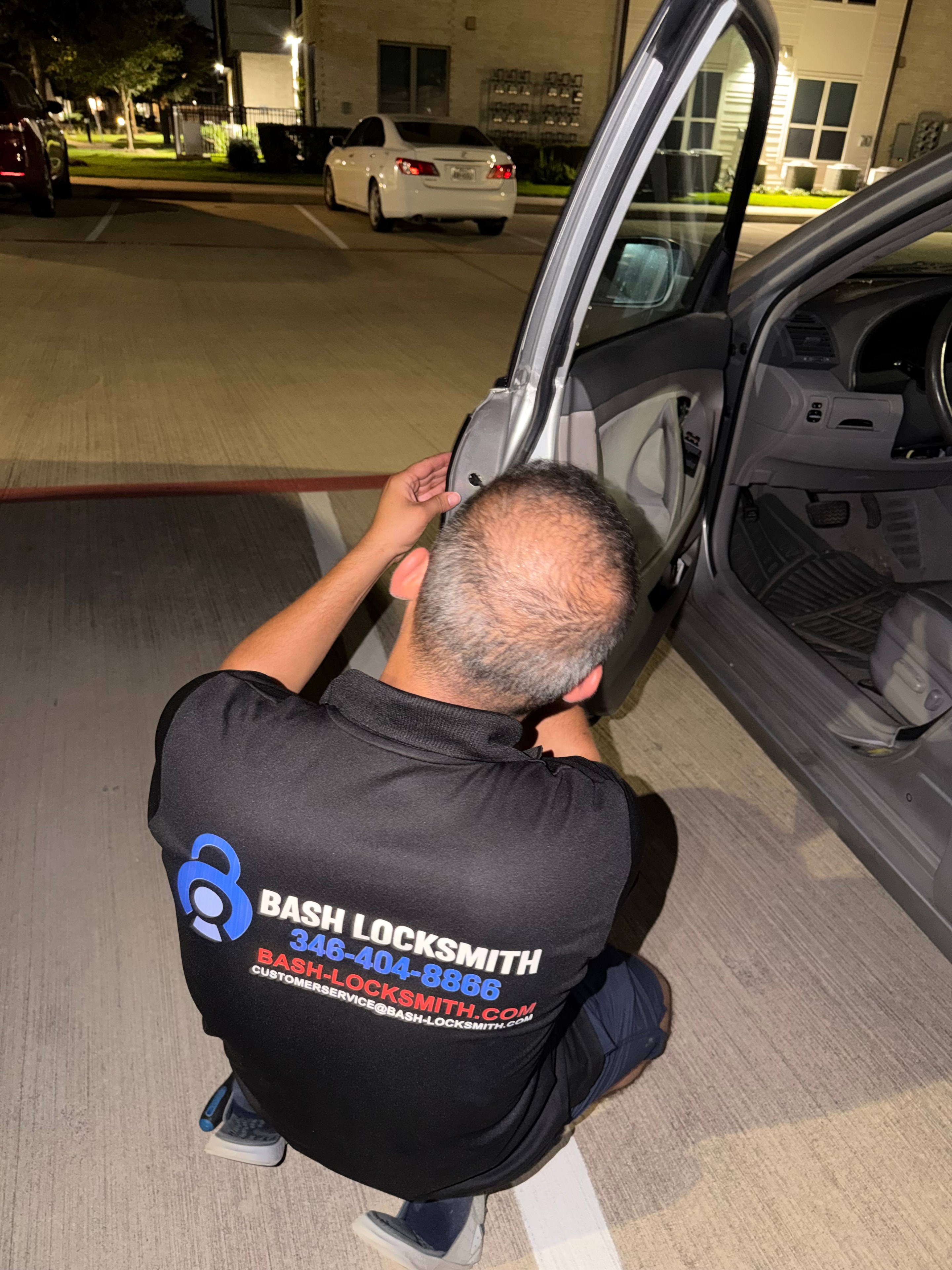 Locksmith working on car door at night