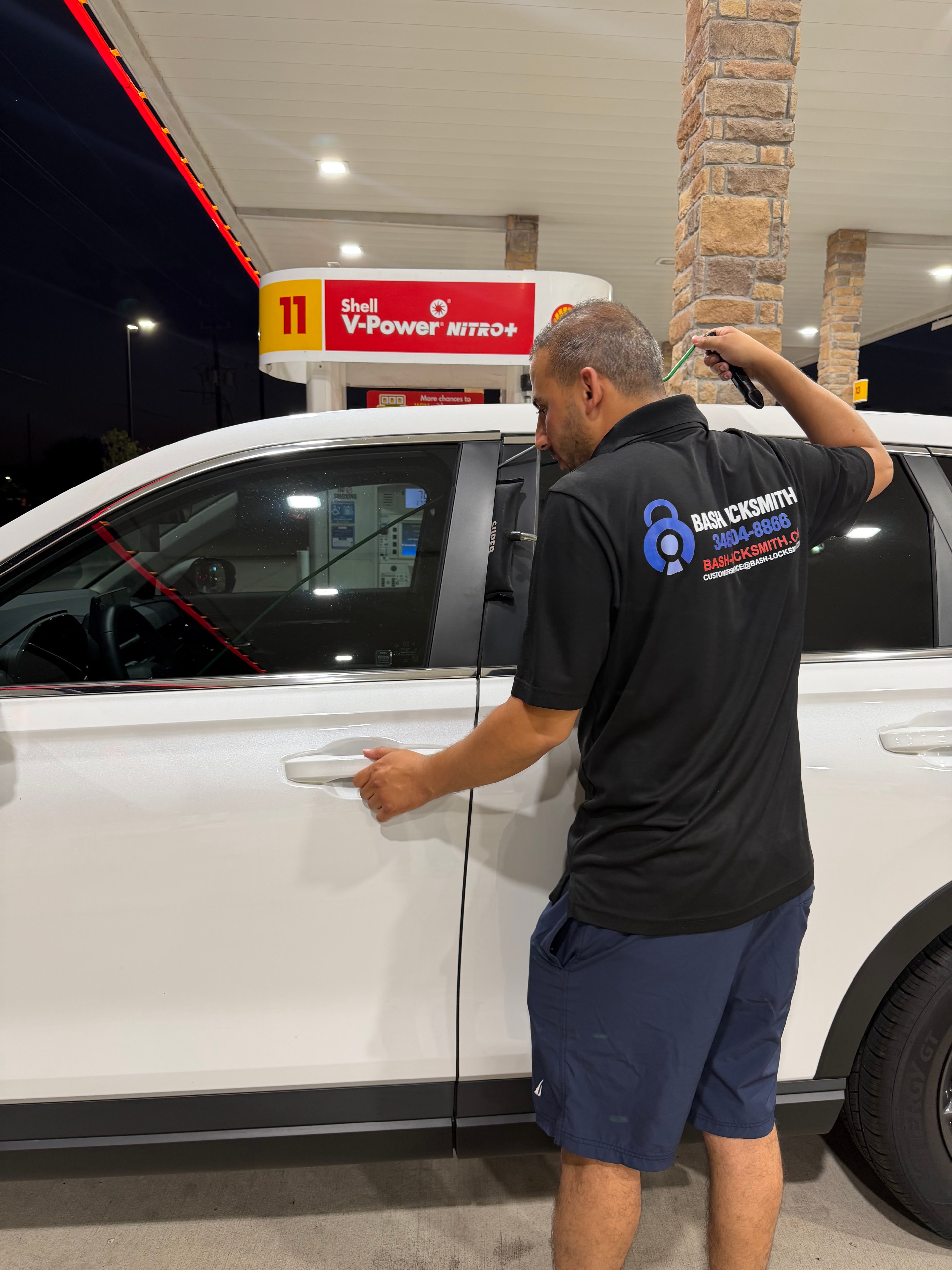 Locksmith unlocking white vehicle at gas station